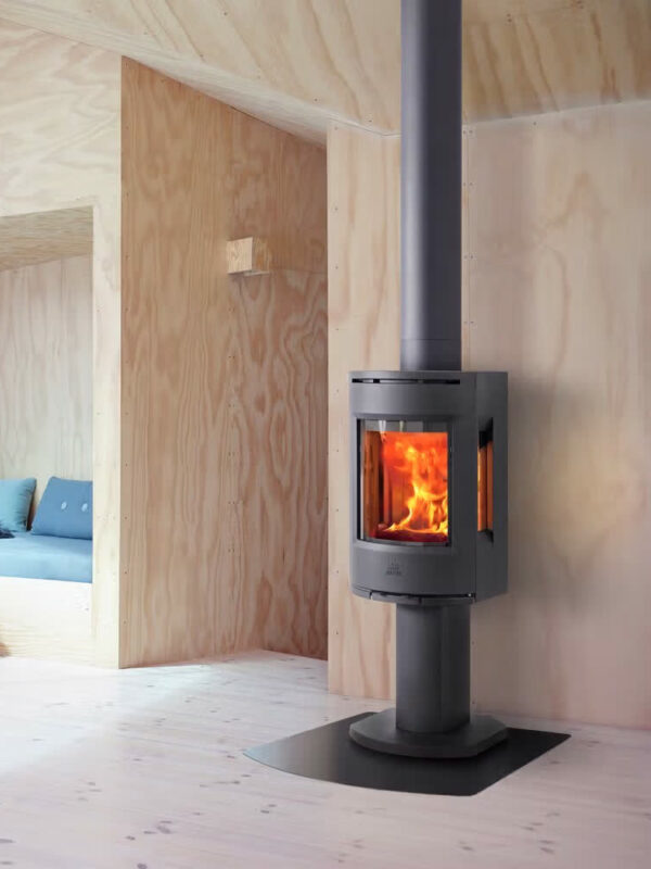 Poêle à bois Jøtul F 137 en fonte, avec porte vitrée, dans un coin salon avec banquette intégrée