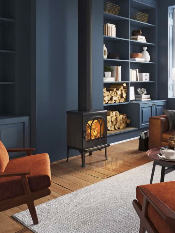 Poêle à bois Jøtul F 200 V2 en fonte, avec porte vitrée, dans un salon bleu nuit