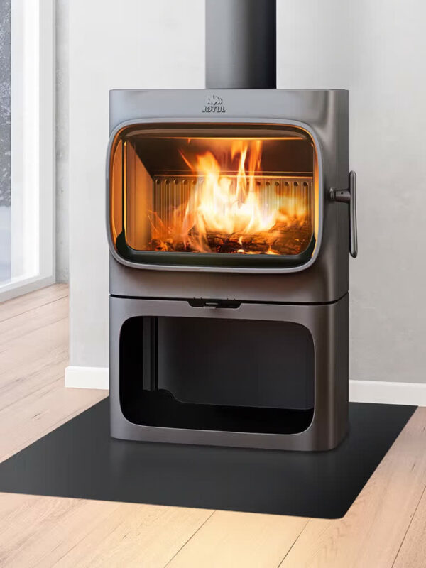 Poêle à bois Jøtul F 305 R B en fonte, avec porte vitrée, dans un intérieur loft avec grande baie vitrée
