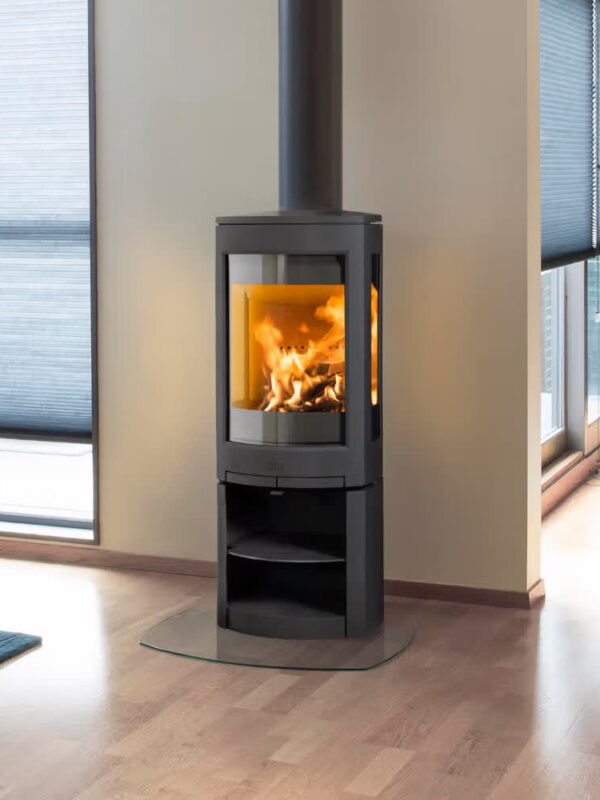 Poêle à bois Jøtul F 371 ADVANCE en fonte, avec porte vitrée, près d'une grande baie vitrée