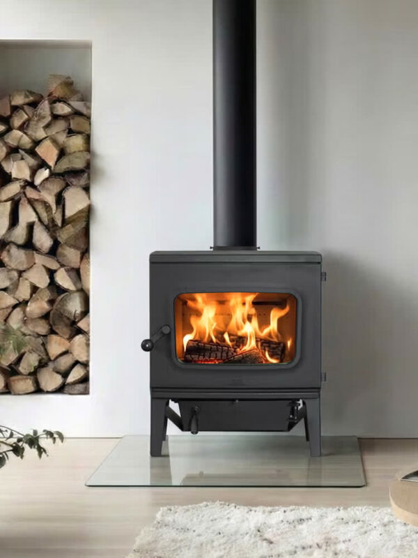 Poêle à bois Jøtul F 405 en fonte, avec porte vitrée, dans un coin salon avec rangement à bois intégré