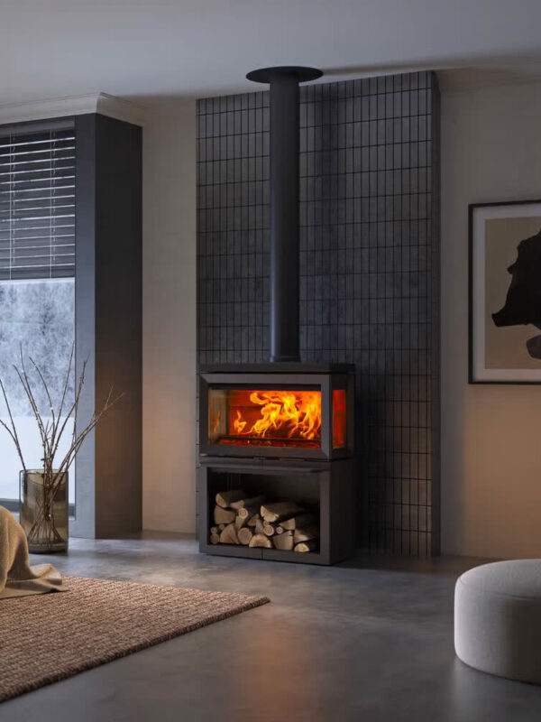 Poêle à bois Jøtul F 620 B en fonte, avec porte vitrée, dans un salon gris épuré à la lumière tamisée