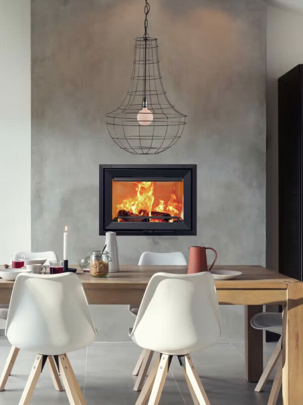 Insert à bois Jøtul I 520 F en fonte, dans une salle à manger, sous une suspension lumineuse