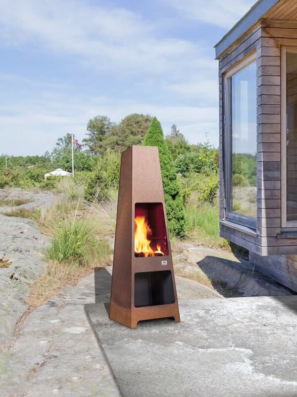 Foyer d'extérieur Jøtul LOKE en acier Corten, sur une terrasse rocheuse en bord de mer