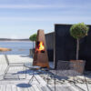 Foyer d'extérieur Jøtul TERRAZZA XL en acier Corten, sur une terrasse en bois avec mobilier d'extérieur